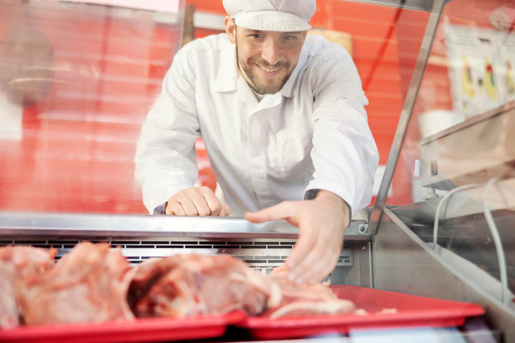 A,Smiling,Butcher,Taking,Fresh,Meat,From,Fridge,And,Selling